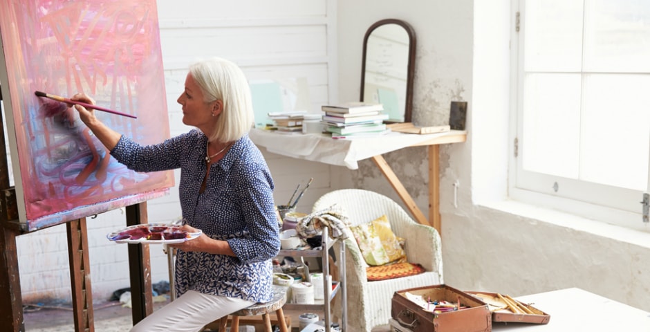 Mujer pintando y poniendo en práctica trucos y hábitos para sentirse a gusto con la vida.