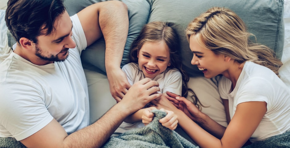 Familia jugando a hacerse cosquillas porque producen alegría y refuerzan las relaciones sociales