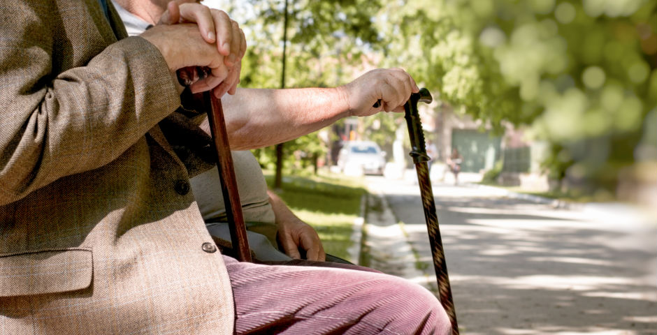 Dos personas mayores sentadas en un banco teniendo una pensión mínima