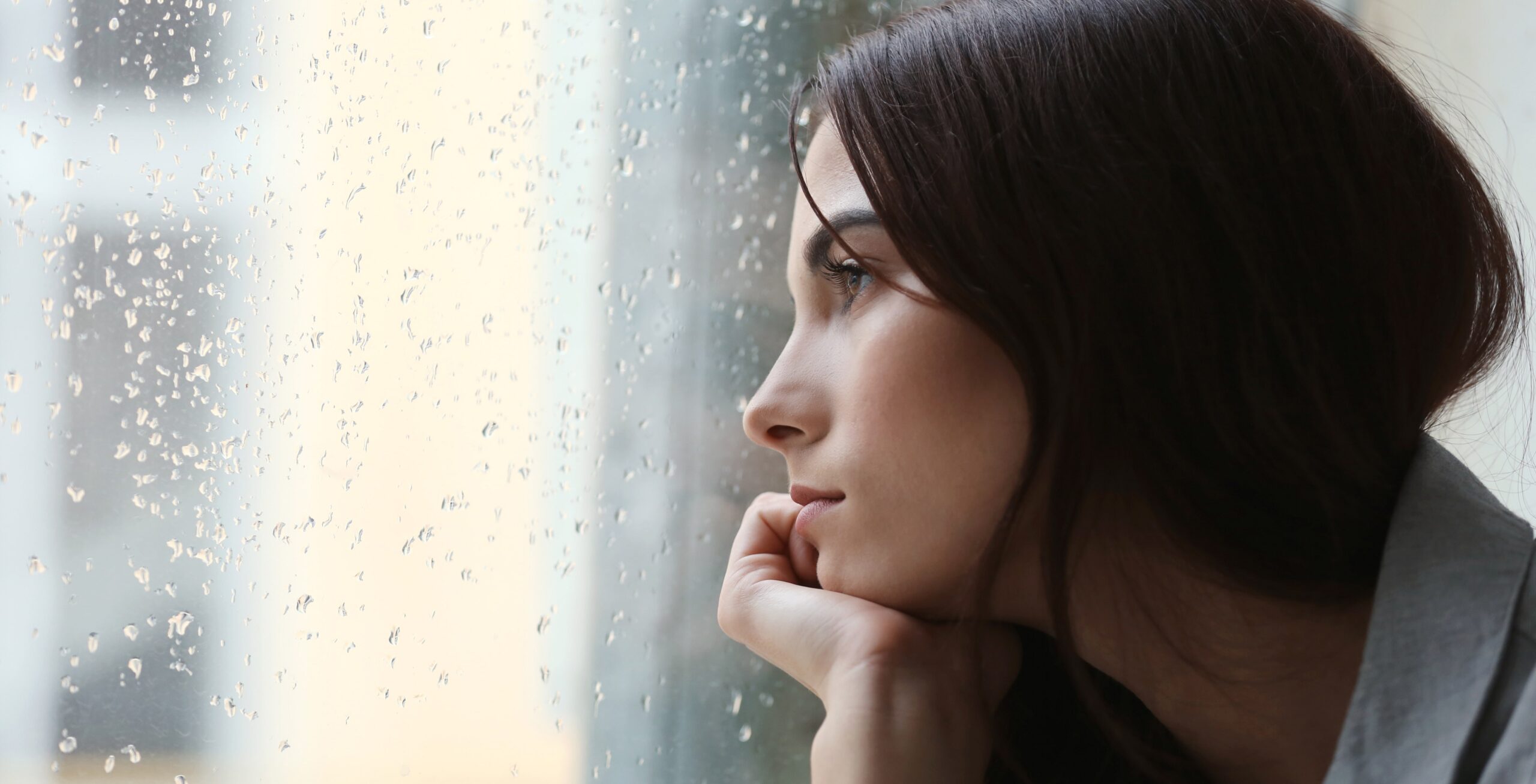 mujer melancólica mirando a través de la ventana