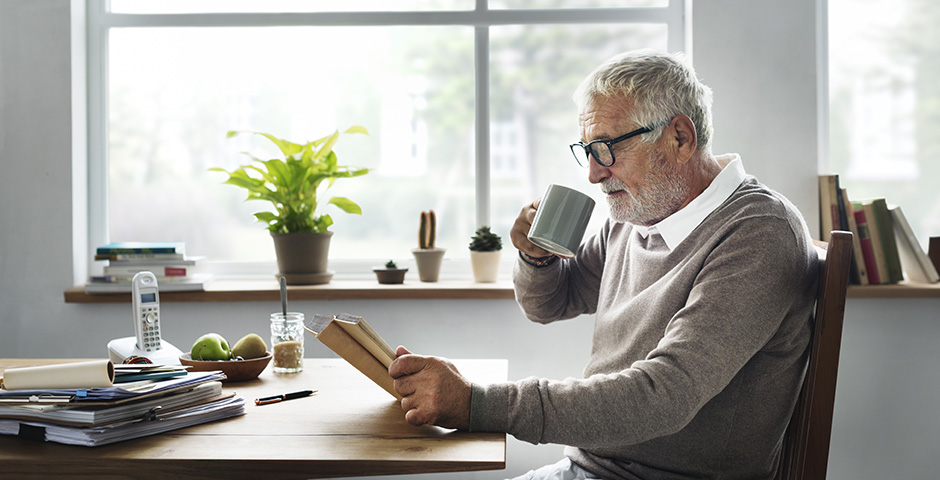 home gran llegint i prenent cafè