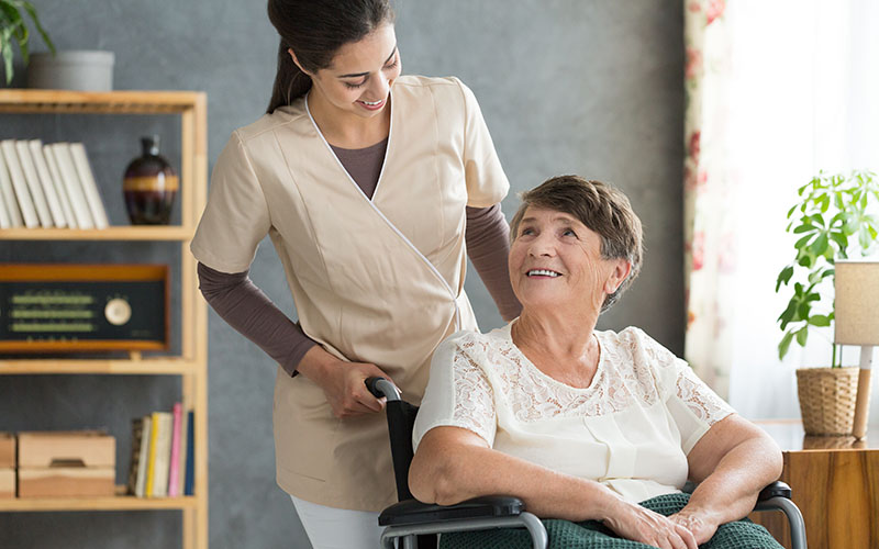 Què és una assegurança de dependència? 2 Dona anciana amb una cuidadora a domicili