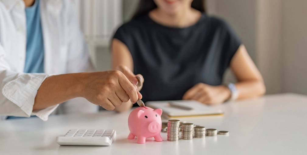Pareja ahorrando dinero en alcancía rosa gracias al plan de renta vitalicia.