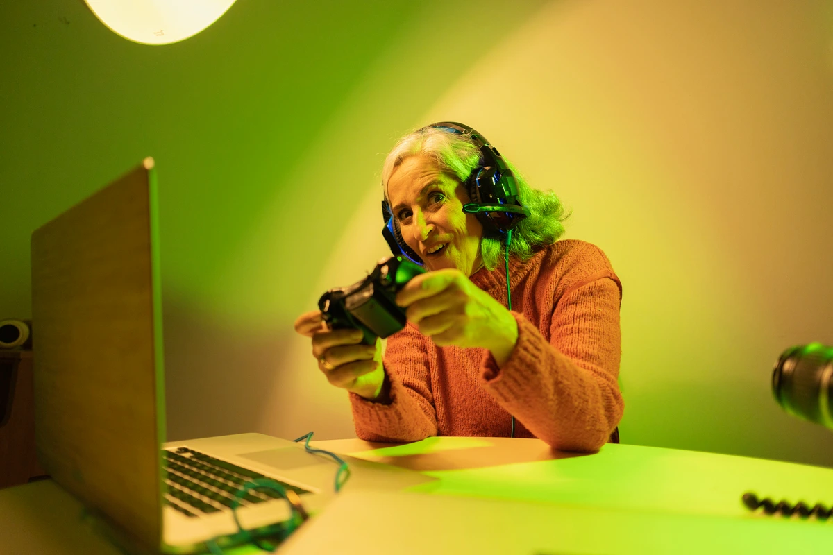 Abuela vengadora disfrutando de su jubilación como streamer, con auriculares y mando.