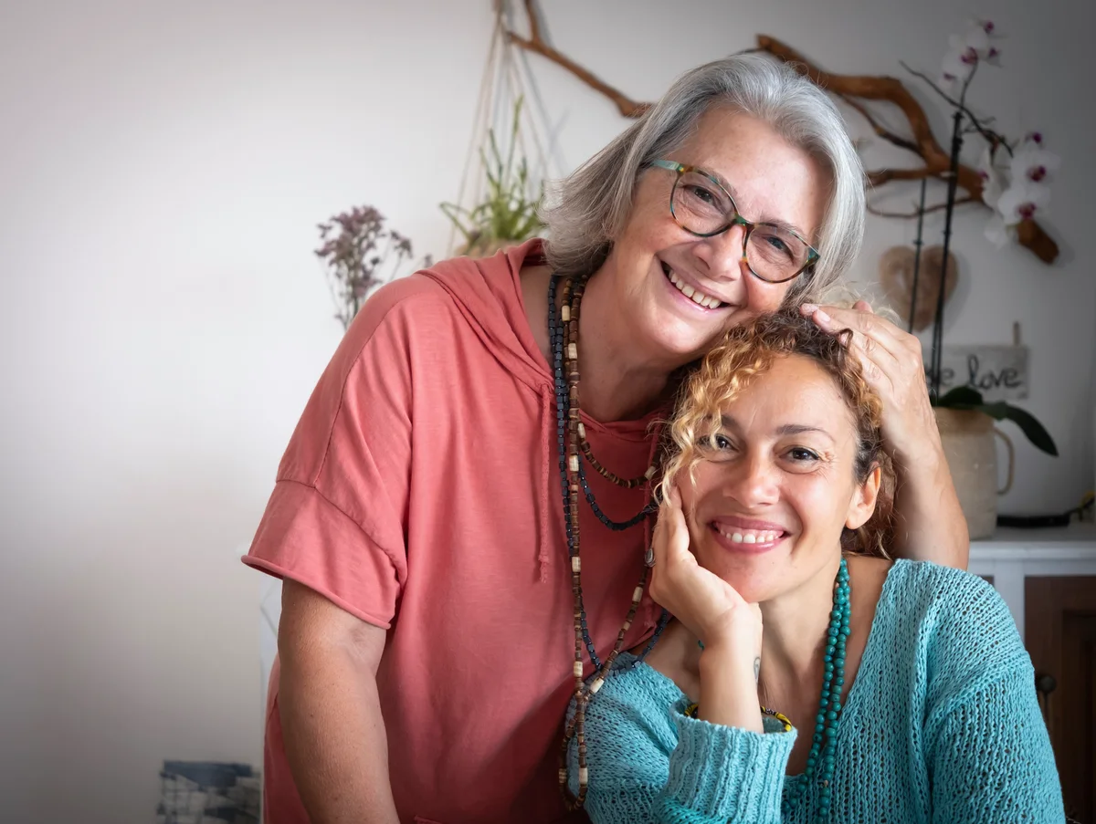 Mare i filla abraçant-se i somrient en un entorn càlid, amb alzheimer hereditari.