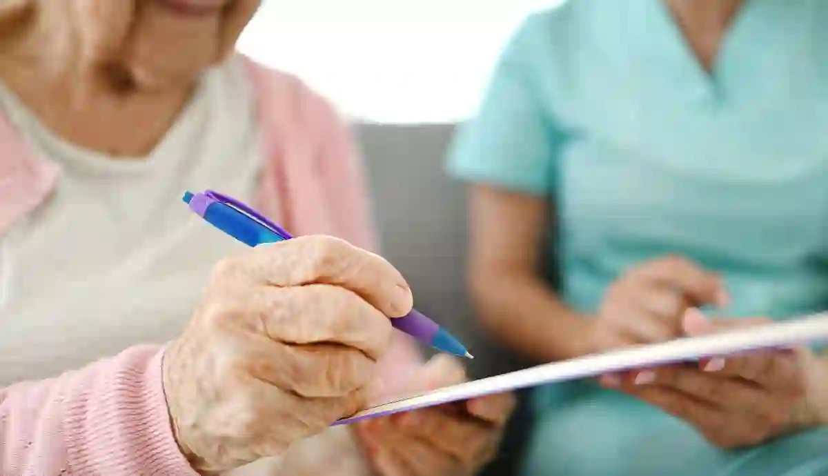 Persona con alzheimer firmando documento asistida por profesional